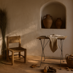 Olé & Co Linnen doek op houten latjes tafel met tinaja en stoel tegen oude Spaanse muur – mediterrane sfeer