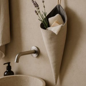 Olé & Co Linnen puntzak met gastendoekje en lavendeltakjes aan de muur van een badkamer. Waskom met kraan.