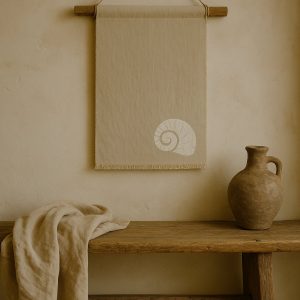 Olé & Co Linnen wandkleed aan de muur met afbeelding van schelp, eronder een bankje met linnen doek en tinaja