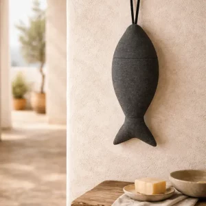 Charcoal grey linnen visje van gestoomd Europees linnen met zichtbare platbinding, hangend aan kalkkleurige muur in landelijke mediterrane setting met zacht natuurlijk licht.